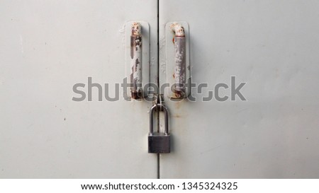 Metal padlock lock the gray metal door for safety.