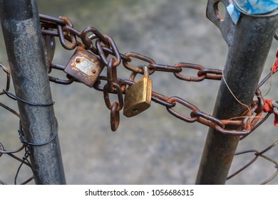 Metal padlock with scratching on skin locked rusty chains in sunrise, Brass lock was worked with chain and old wire mesh door, selective focus - Powered by Shutterstock