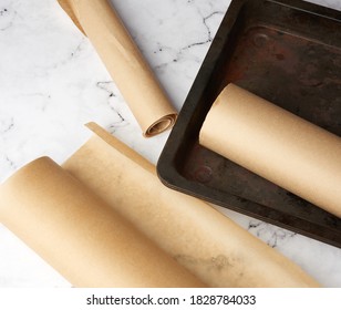 Metal Pan And Rolls Of Brown Parchment Paper On A White Table, Top View