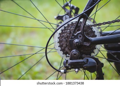 Metal parts of the bike-chain, rear cassette, switch, brakes, gear levers on the background of blurred grass. A sprocket on a Bicycle wheel, a close-up of a Bicycle gearbox and a black electric motor.