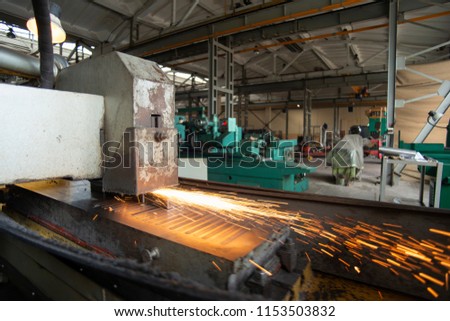 Metal parts on a flat grinder are treated with an abrasive wheel, sparks fly from under the circle, wide-angle photos