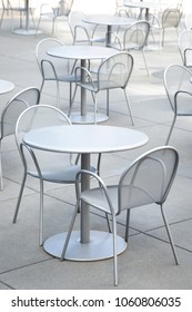 Metal Patio Furniture With Sets Of Empty Tables And Chairs In The Square Of A Public Park