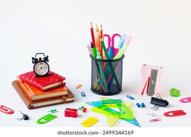 Metal pencil holder filled with colored pencils, with colorful school supplies on a white surface - Powered by Shutterstock