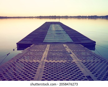 Metal pier with round holes. Evening or sunrise on a lake or river. Calm landscape. Rusting of metal structures. A pier for small cobbles and boats. Palic, Serbia. Travel, tourism and fishing - Shutterstock ID 2058476273