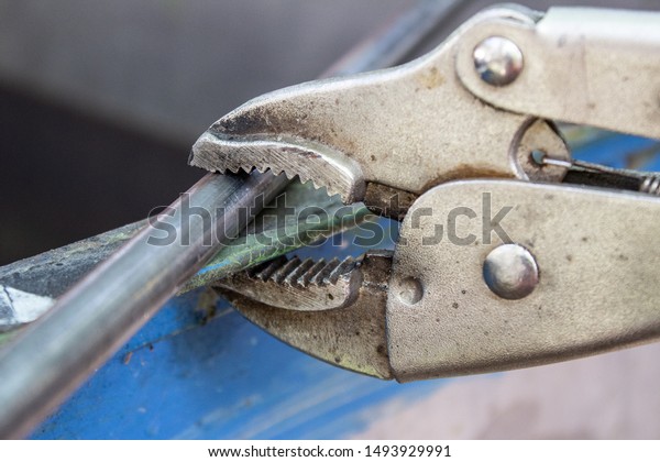 metal pipe\
clamped with Locking pliers (also known as Vise-Grips or a Mole\
wrench or a vice grip). Close up\
macro