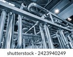 Metal pipes and containers in an industrial building, view from bottom to top. Industrial concept background