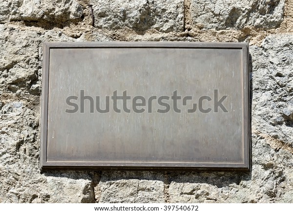 Metal plaque mounted\
on an old stone wall.