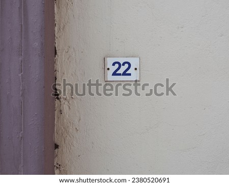   Metal plate with number twenty two, attached to the wall of the building.        