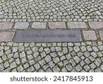 A metal plate on the ground marking the site of the now demolished Berlin Wall, originally built in 1961 to encircle West Berlin primarily to prevent East German citizens fleeing to the West.