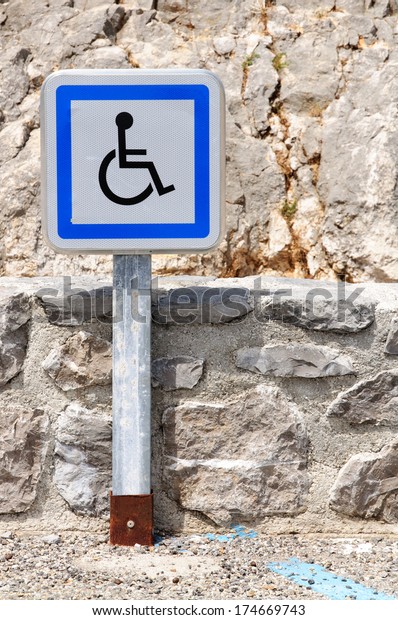 A metal pole with a disabled parking slot sign at a\
parking place