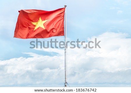 Metal pole with waving banner. Red flag with yellow star, blue sky with clouds in background. Rippled texture. National flag of Vietnam. Popular country for tourism. Famous tourist destination.