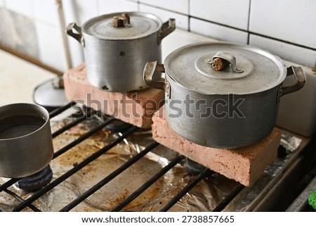 Metal pot elevated with bricks on stove, creating makeshift heating for a home without central heating, alternative solution for warmth during cold winter months in a Ukrainian kitchen