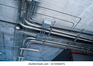 Metal power pipe on ceiling. Electrical conduits system, metal pipeline installed on building ceiling.