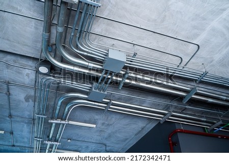 Metal power pipe on ceiling. Electrical conduits system, metal pipeline installed on building ceiling.
