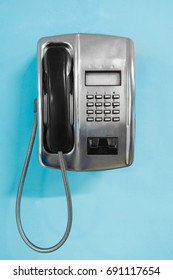 Metal Public Telephone On Blue Wall. Old Payphone Concept