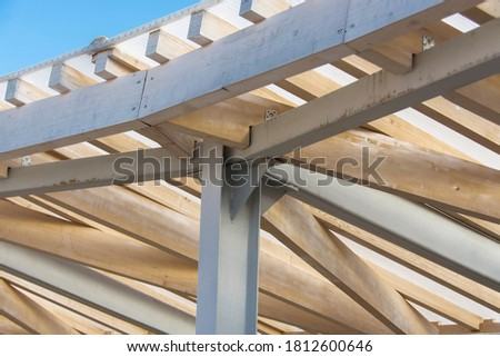 a metal rack with traces of rust supports the roof with wooden beams