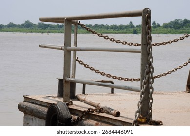 A metal railing with chains on a structure on a dock next to a body of water