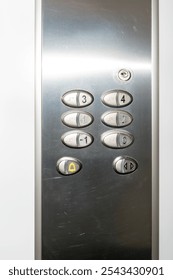 Metal reflective elevator control panel with yellow alarm bell. Lock for service personnel at the top. Braille dots on the buttons for persons with bad or missing eyesight.