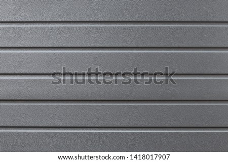 Metal reflective gray grooved surface. Grey metalline background, texture. Metallic gate in the line close-up. Abstract ribbed textural iron wall pattern.