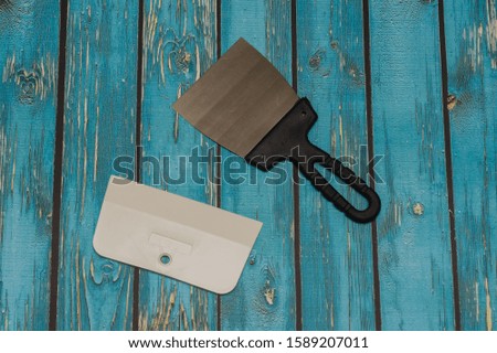 metal and rubber spatulas for repair work on a blue wooden background