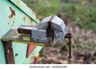 metal rusting bench vice attached to a green trailer, with visible rear lights