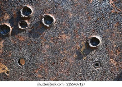 A metal rusty plate of the armor of an old mortar with traces and bullet holes. A close-up fragment. Russia, Ivangorod fortress. 
