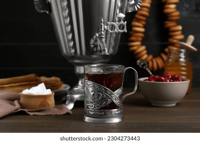 Metal samovar with cup of tea and treats on wooden table - Powered by Shutterstock