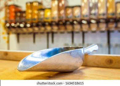 Metal Scoop In Zero Waste Shop With Bulk Dry Food Dispenser In The Background, Defocused