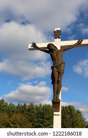 Metal Sculpture Of Jesus Christ On White Wooden Cross Outside