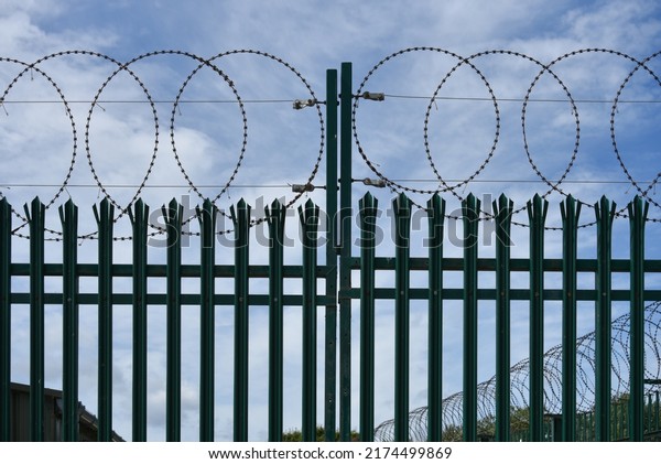 Metal security\
gates topped with razor wire.\
