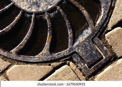 Metal Sewer Manhole Cover On A Stone Road. Urban Stormwater System. Close-up