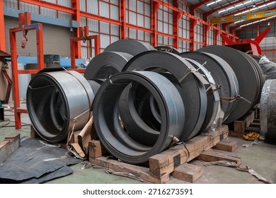 A metal sheet rolling machine processes raw material in an industrial factory, showcasing metal fabrication and manufacturing equipment in action.