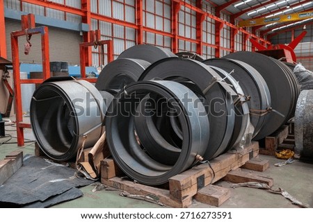 A metal sheet rolling machine processes raw material in an industrial factory, showcasing metal fabrication and manufacturing equipment in action.