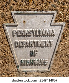 A Metal Sign In The Shape Of A Keystone With Pennsylvania Department Of Highways On It Shown On A Concrete Wall. The Plaque Signified Property Owned And Maintained By That Department