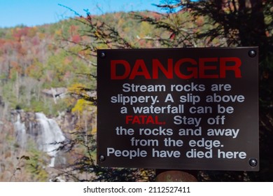 A metal sign that says DANGER Stream rocks are slippery. A slip above a waterfall can be FATAL. Stay off the rocks and away from the edge. People have died here.