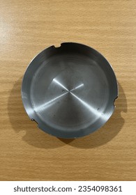 Metal silver ashtray from top view isolated on wooden desk background