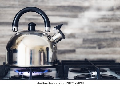 A metal silver teapot on a gas stove in the kitchen