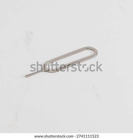 Metal sim card ejector tool lies isolated on a white background for mobile phone sim card removal.