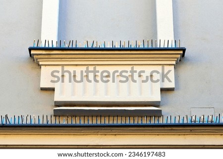 metal spike anti-roosting or bird prevention and repellent strip. bird control, pigeon prevention concept. elevation detail. sharp needles. old European building exterior stucco detail. architecture