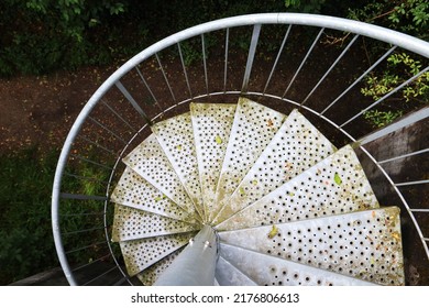 Metal spiral staircase, view from the top down, in the forest. Partially covered with moss, rust and foliage, with perforated sheet. Mystical - Powered by Shutterstock