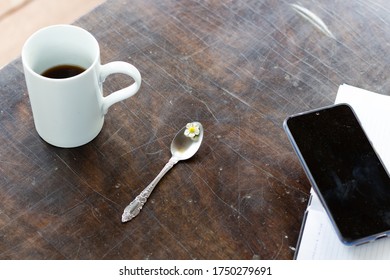Metal Spoon With Strawberry Flower, Cup Of Coffee, Smartphone On Paper Dairy  On Wooden Table