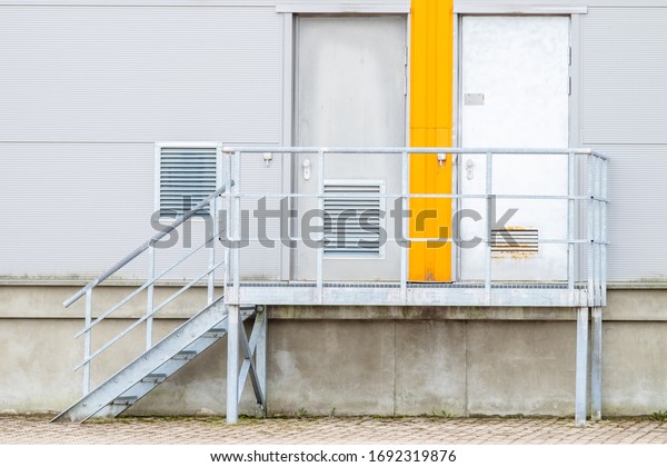 Metal stairs\
leading to doors. Entrance and exit orange color. Divide. Choice.\
Small steps. Ventilation. Thinking of reason. Come and go. Stable\
ground. Light gray aluminum\
wall.