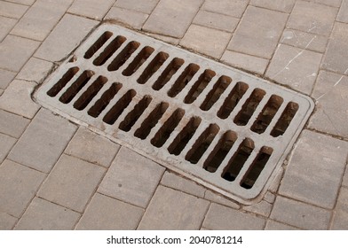 Metal Storm Grate On Rectangular Gray Paving Slabs