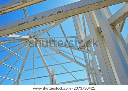 A metal structure made of square and rectangular pipes against the background of a cloudless sky