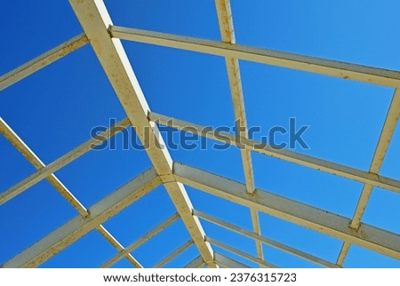 A metal structure made of square and rectangular pipes against the background of a cloudless sky