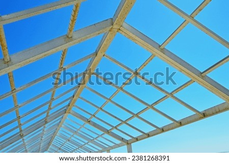 A metal structure made of square and rectangular pipes against the background of a cloudless sky. Selective focus