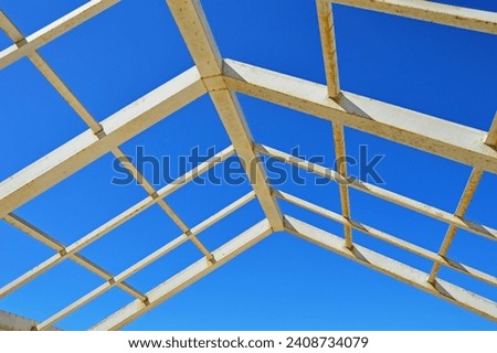 A metal structure made of square and rectangular pipes against the background of a cloudless sky