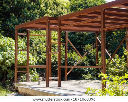 A metal structure standing on a concrete slab among the trees. Construction of a metal frame building