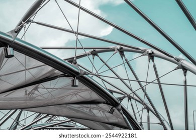 Metal structures with mesh and cables under a blue sky, forming an abstract modern architectural design - Powered by Shutterstock