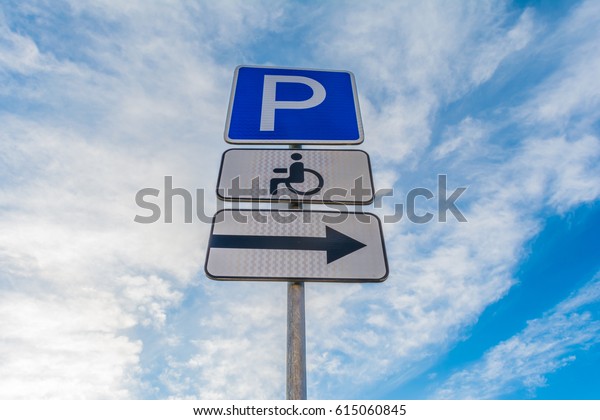 Metal support with traffic signs\
parking place, right signboard, sign of a place for the disabled\
against a blue sky with white clouds, abstract\
background